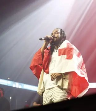 Singer draped in the Tonga flag under stage lights