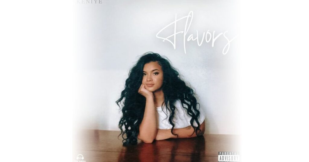 Album cover for Keniye's single 'Flavors,' featuring a Polynesian artist with long, curly hair seated at a wooden table, wearing a white shirt.